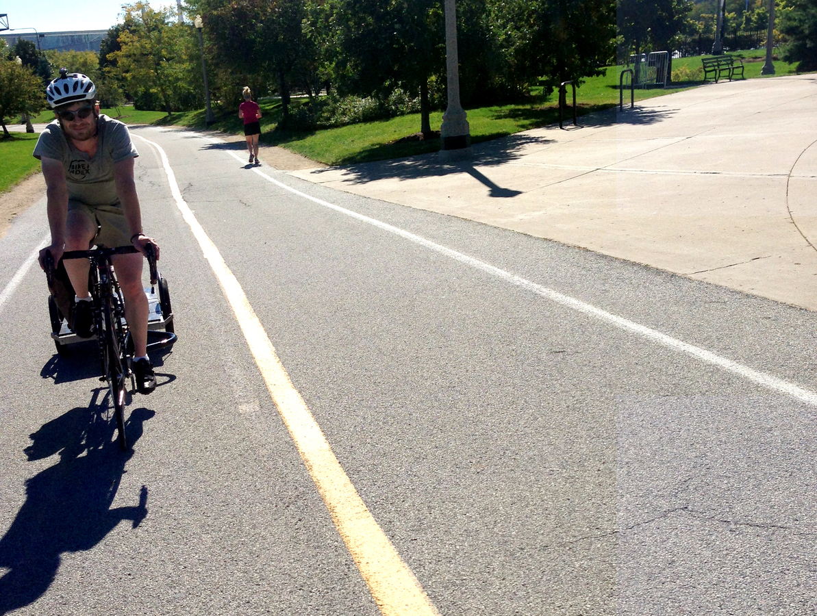 Seth riding home with the Bike Index sign and his Surly trailer